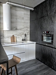 Maintaining the overall minimalist look while maximizing storage and functional space in the kitchen was another challenge. Here the space is dominated by luxurious onyx wall tiles with nothing hiding them from your eyes but white extraction hood over the cook top. Everything else is built into the black cabinets which take up the whole wall.