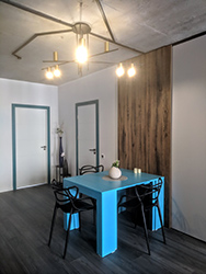 Large burnt walnut wall panel dominates and connects the dining area to create as cozy alcove as possible given the initial conditions. Bold blue color was chosen consciously to further draw the attention in to the table itself instead of abundance of doors and other connected areas. If expanded, this table can be up to 6 feet long and house even the largest family for the dinner.