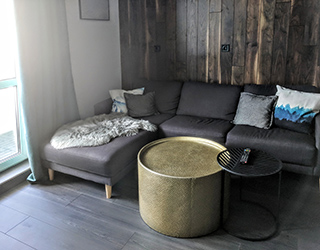 Dark green curtain, walnut wall panels and dark gray sofa combine into a cozy alcove.