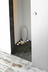 As you slide the bathroom door, there's a small corner with a decorative vase and pebbles.