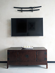Oriental inspired TV cabinet with katana swords mounted on the wall.